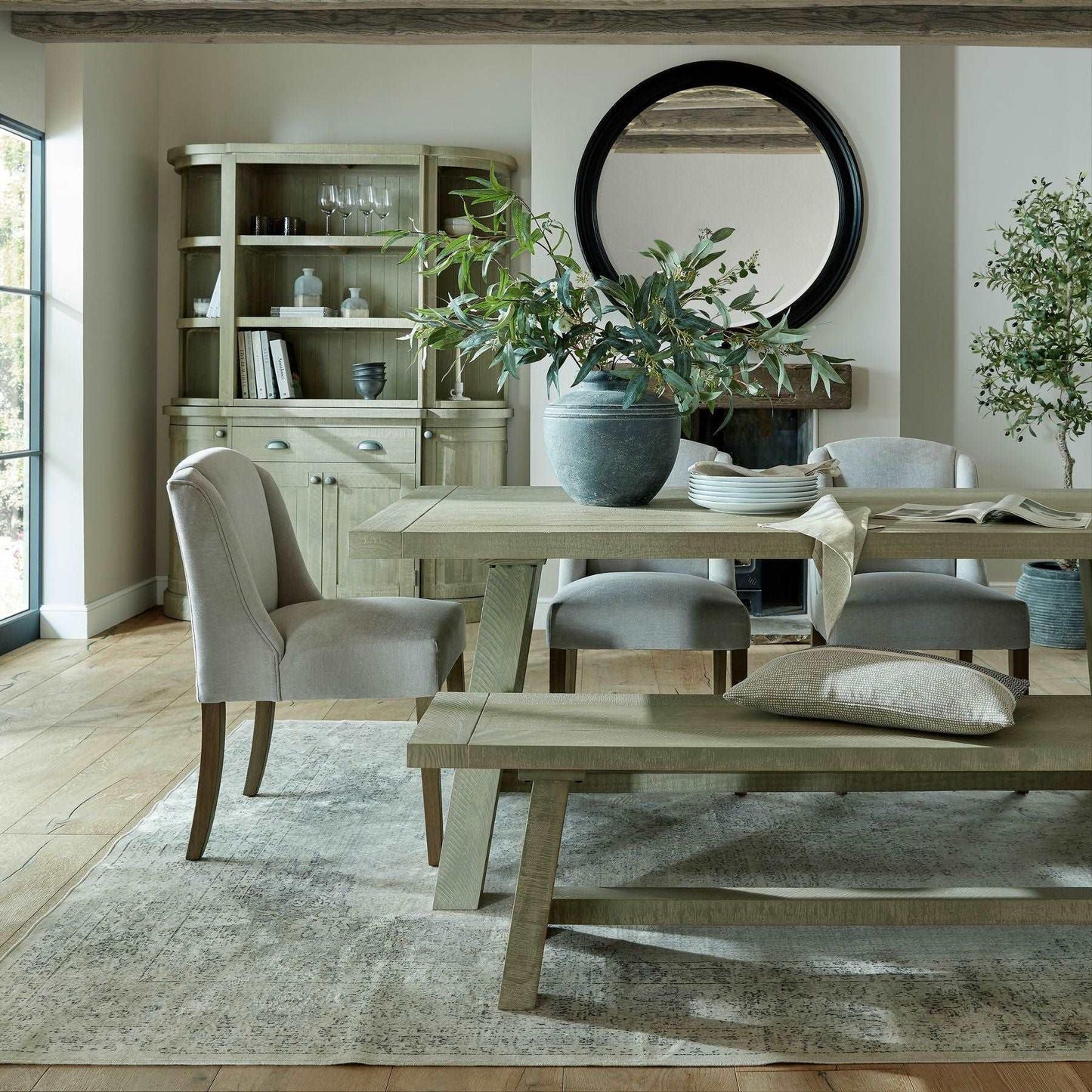 Modern dining room with handcrafted wood table, neutral chairs, bench, and potted plant centerpiece