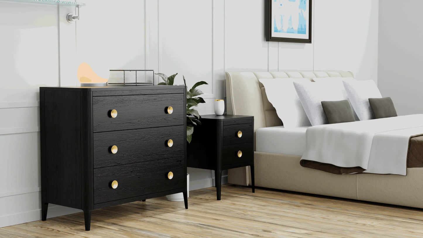 Modern black wood chest of drawers and bedside table with gold handles in a stylish bedroom