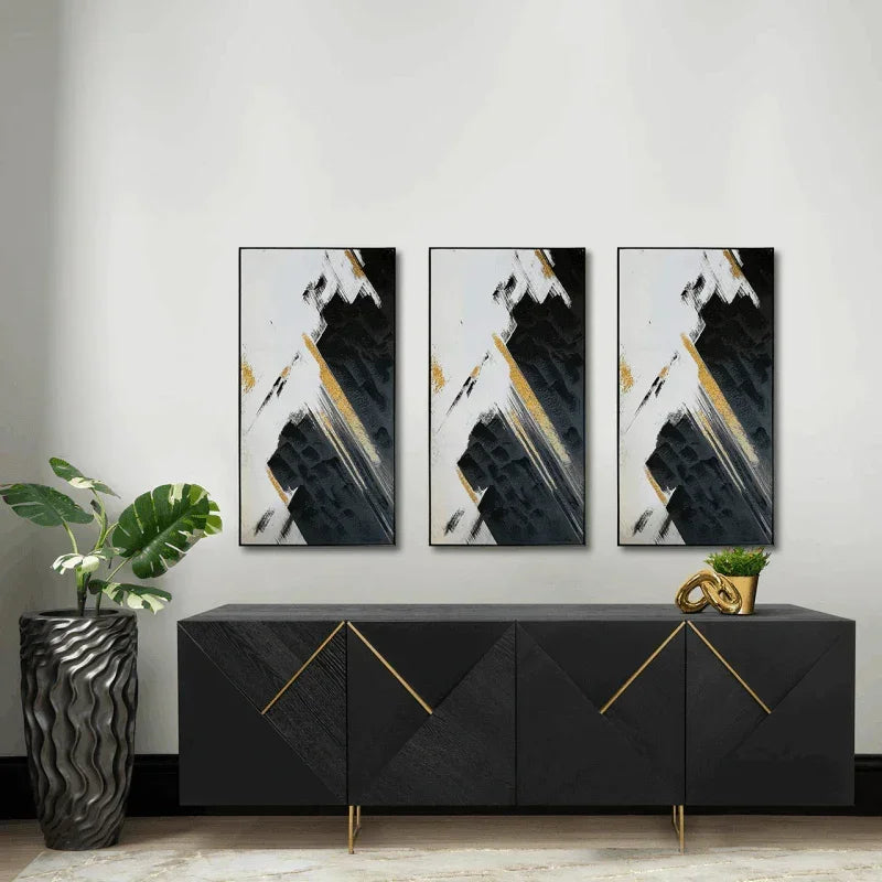 Modern black sideboard with gold accents, abstract art triptych, and indoor plant in vase
