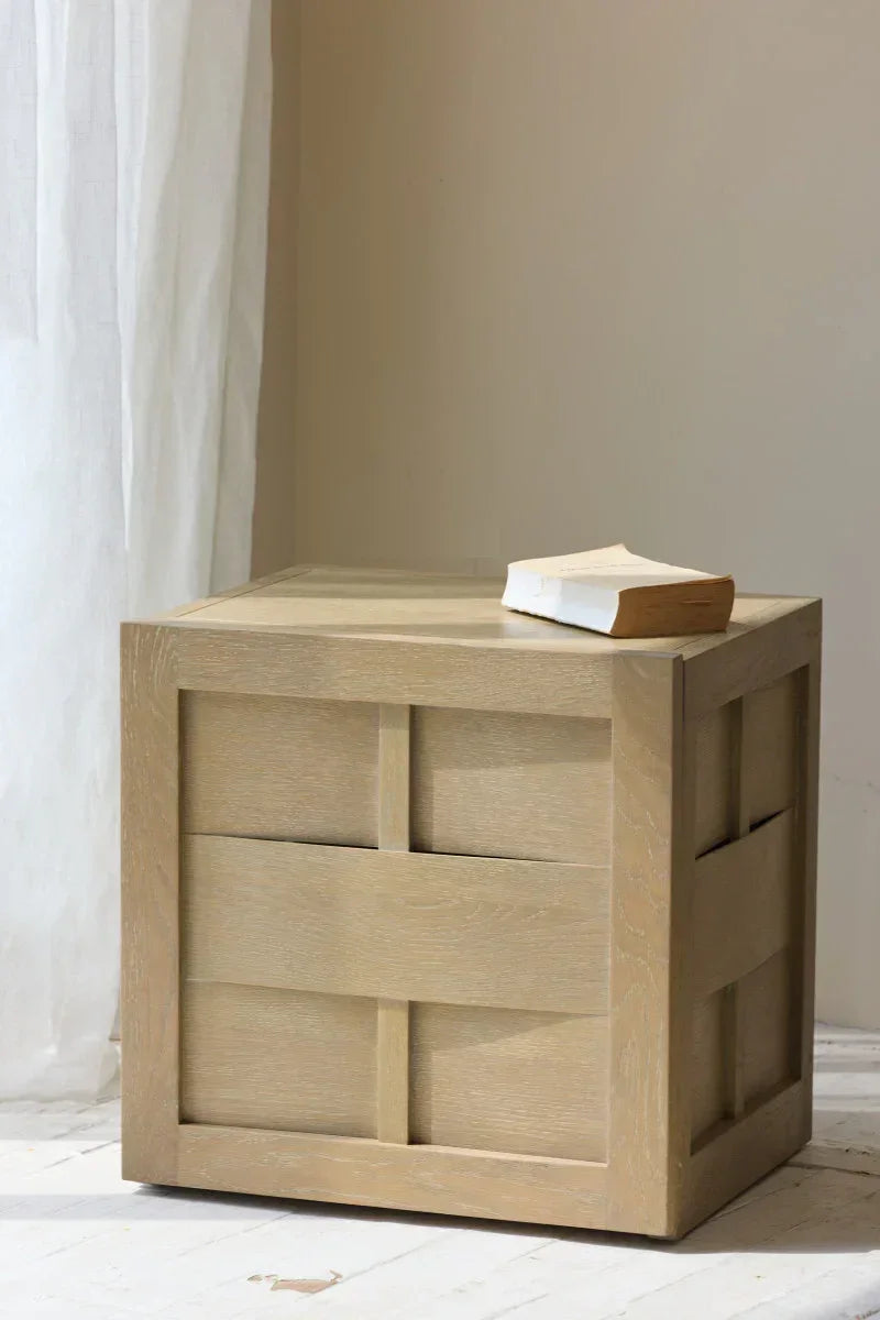 Modern light wood nightstand with square paneling, book on top, minimalist interior