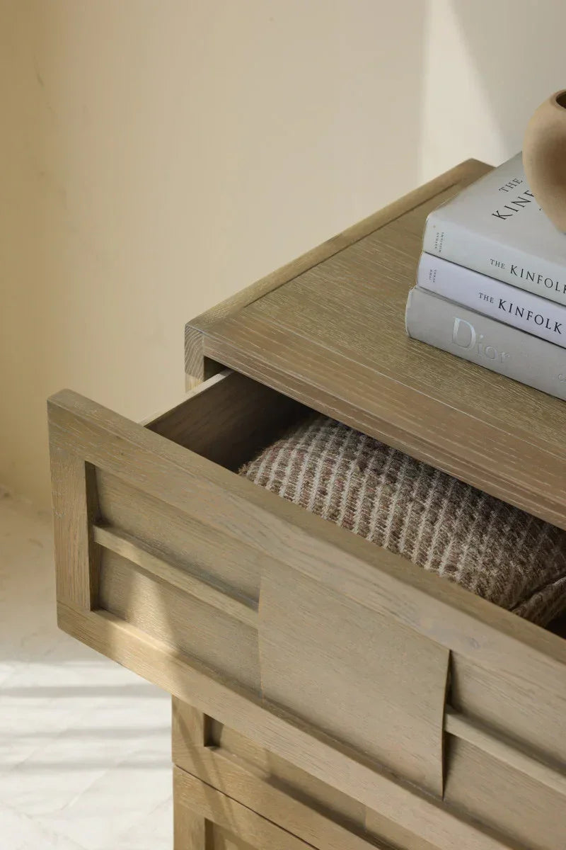 Handcrafted light wood drawer with geometric detailing, open to reveal a textured blanket, books on top